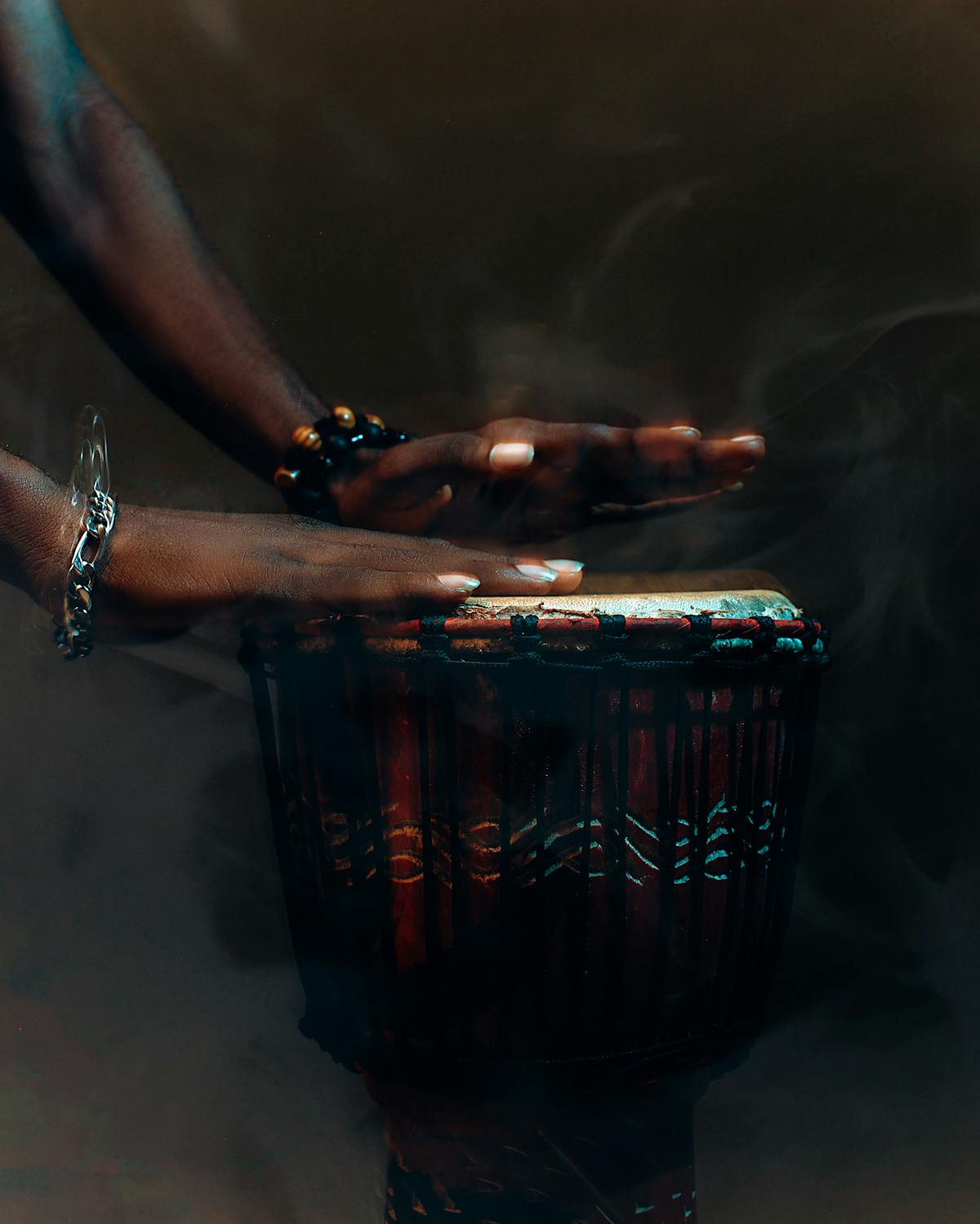 Hands mid-beat on a carved djembe drum
