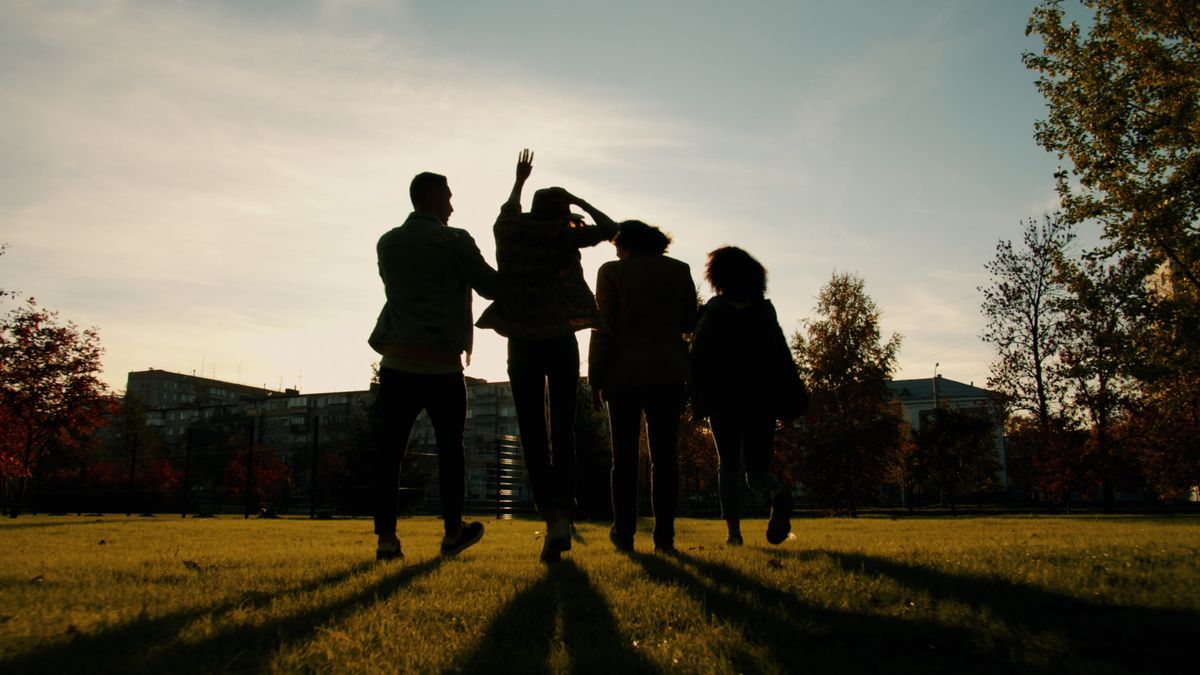 Friends silhouetted against a sunset sky, walking together