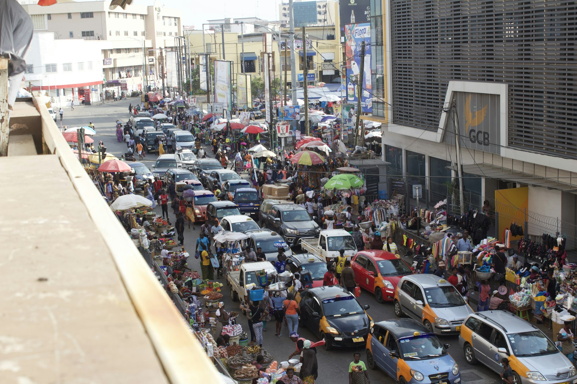 A busy everyday street scene with market stalls and taxis in central Accra