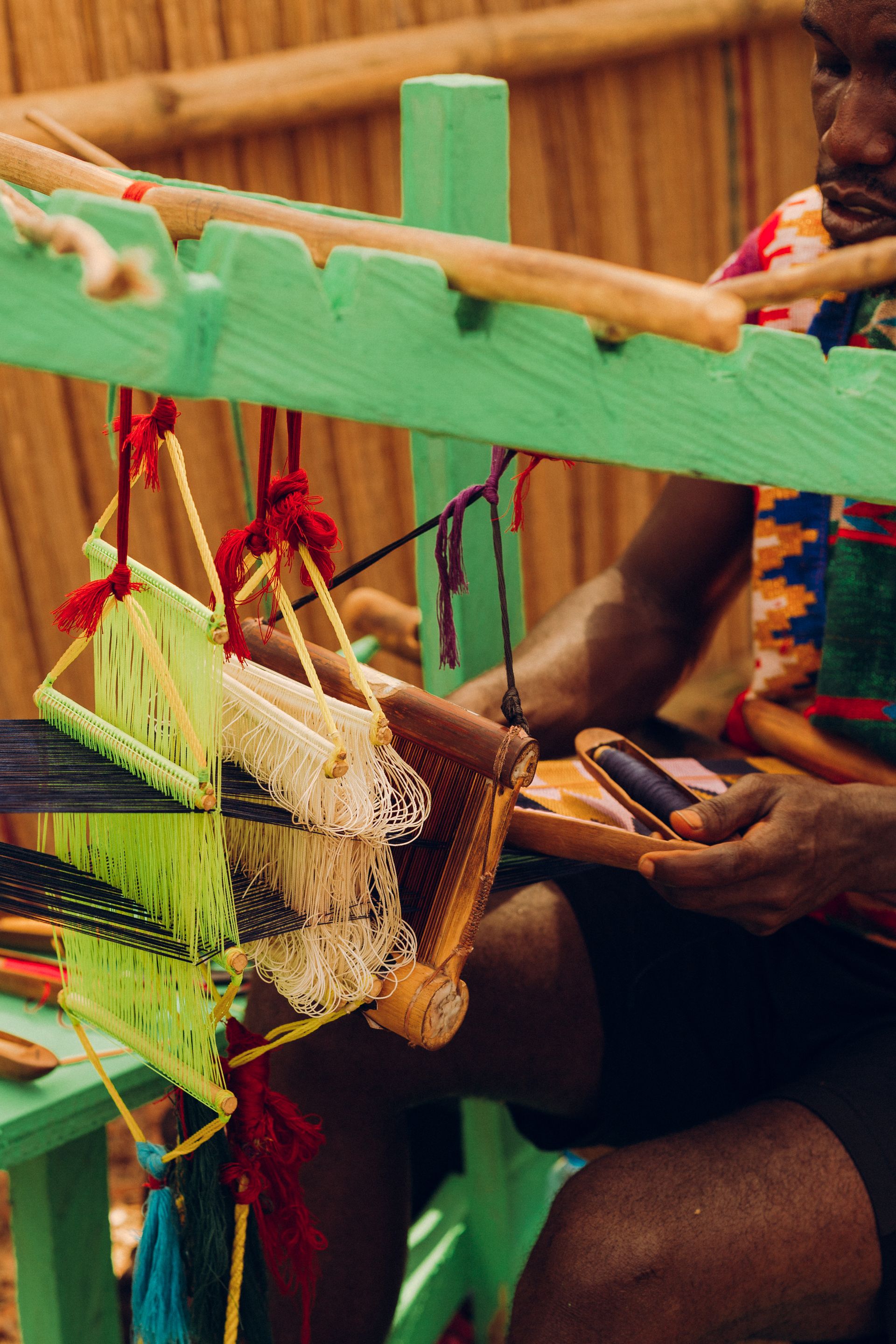 A craftsman weaving colourful kente cloth on a traditional strip loom