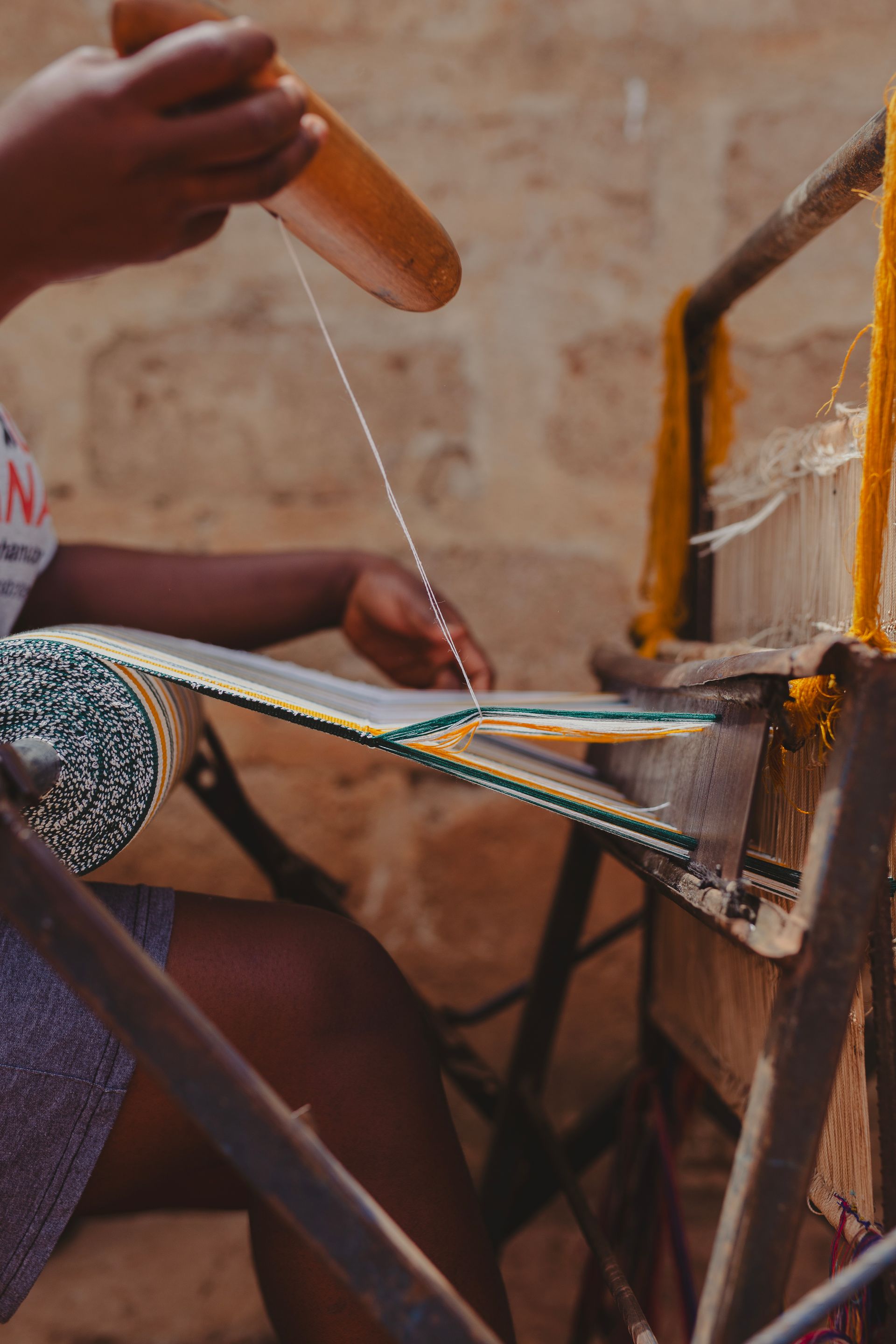 Close-up of hands weaving kente fabric on a loom in Ghana